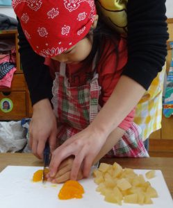所沢市のあかね保育園の年少組・いちょう組でクッキングをし、フルーツを切っている画像